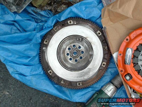 clutch disc and flywheel on blue tarp, drill nearby