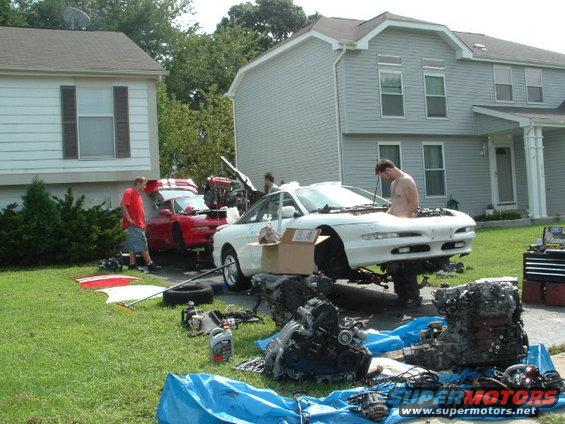1996 Ford Probe and a red car with hoods open, engines removed, in a residential yard