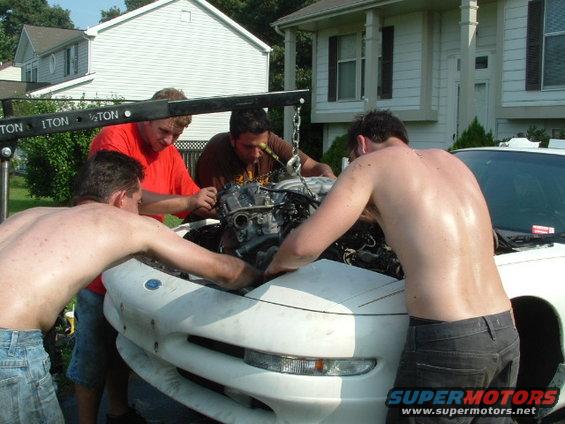 Guys pulling engine out of a 1996 Ford Probe with an engine hoist
