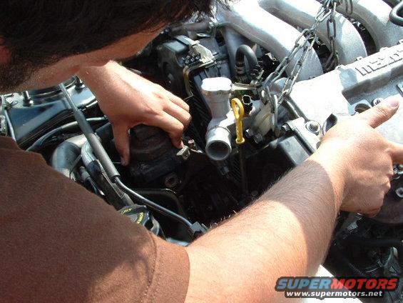 guy working on car engine, chain attached to engine block