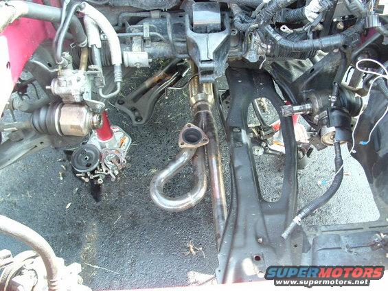 car engine bay, showing exhaust manifold and drive axle components