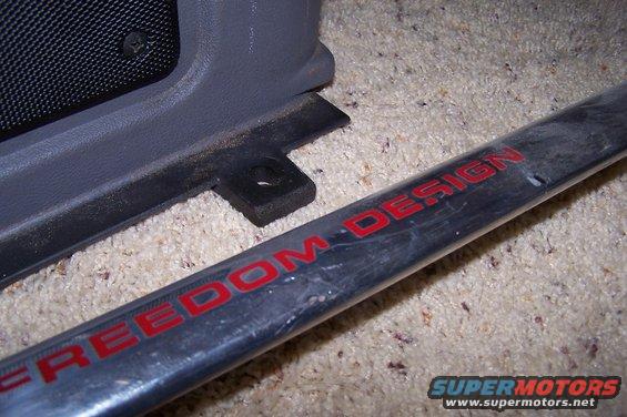 Close-up of a car interior trim piece and a metal bar with red text reading "FREEDOM DESIGN"