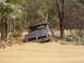 1995 Ford Bronco - A dark-colored Ford truck is stuck in thick mud, with trees and foliage surrounding the area.
