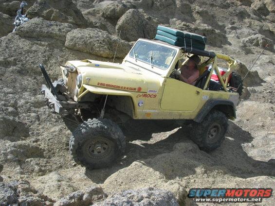 Yellow Jeep climbing rocky terrain, has '2 Big Broncos 4x4 Club' and 'CalROCS' decals on the side