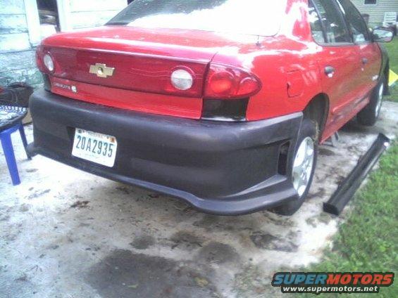 red sedan, possibly a Cavalier, with a black aftermarket rear bumper and a license plate reading 20A2935