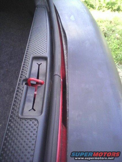 Close-up of a red car door latch mechanism inside a car door jamb