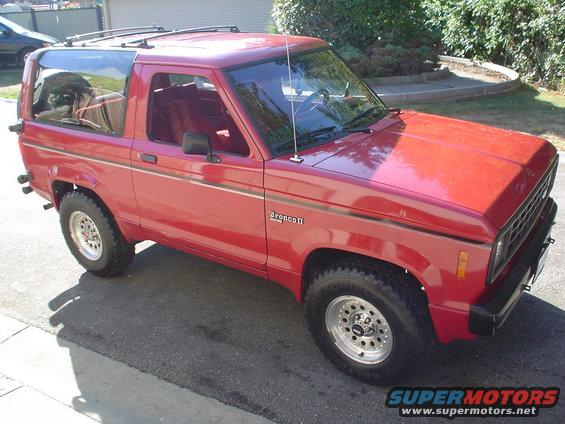 Red 1988 Ford Bronco II parked on asphalt, side view with front quarter visible