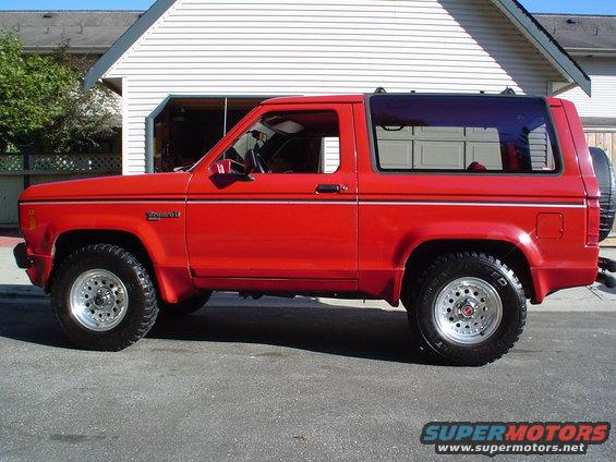 Red 1988 Ford Bronco II parked in front of a garage