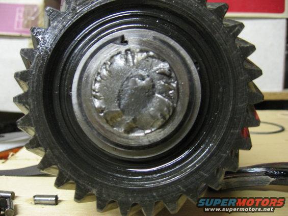Close-up of a damaged metal gear with a circular impression in the center