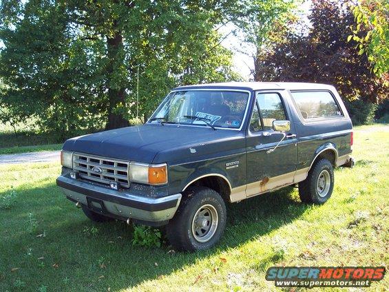 Dark blue 1987 Ford Bronco with tan trim parked on grass