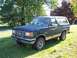 1987 Ford Bronco - This 1987 Ford Bronco is seen from a 3/4 front angle, parked on a grassy area with trees in the background.