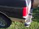 1987 Ford Bronco - Rear view of a 1987 Ford Bronco showing the taillight, bumper, and a section of the two-tone paint with rust.