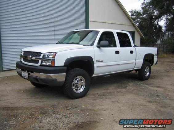 White 2003 Chevrolet Silverado 2500 pickup truck parked outside a garage