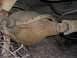 1983 Ford Bronco - The underside of a vehicle shows a heavily rusted rear differential and part of the driveshaft.