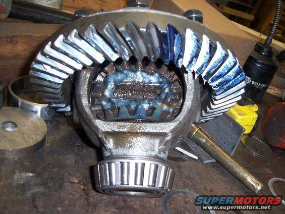 Close-up of a differential gear assembly with blue and white grease on the teeth. Bearings are visible