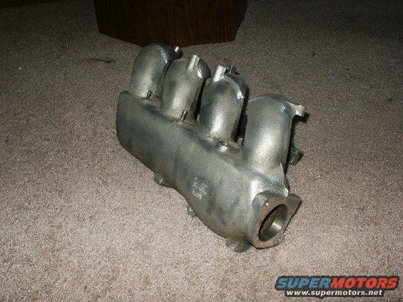 Aluminum intake manifold with four runners, resting on carpet