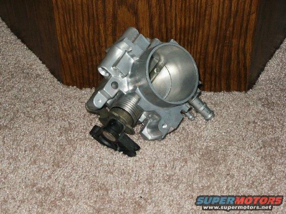 Aluminum throttle body with black plastic actuator on a carpeted surface