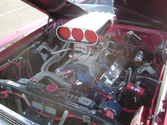 Engine bay with a large Holley air intake and V8 engine. Some hoses and wiring are red