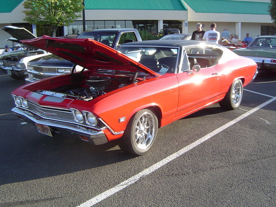 Red 1969 coupe, hood open, 3q-front view. Chrome wheels