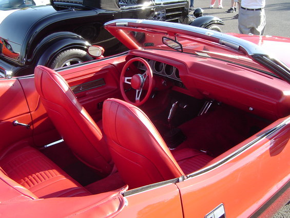 Red interior of a convertible with a black car in the background