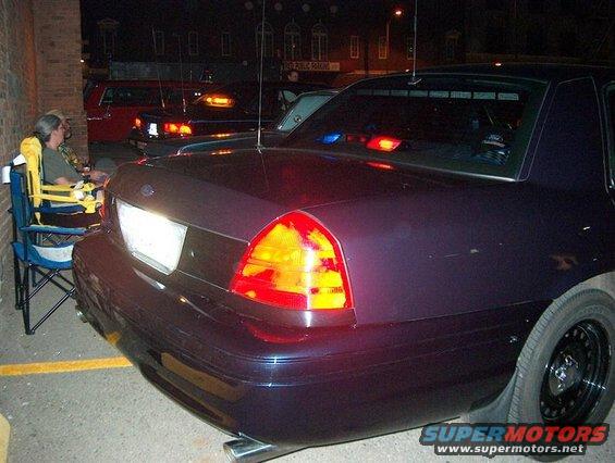 Dark purple 2001 Ford Crown Victoria Police Interceptor, rear view, with police lights on the roof
