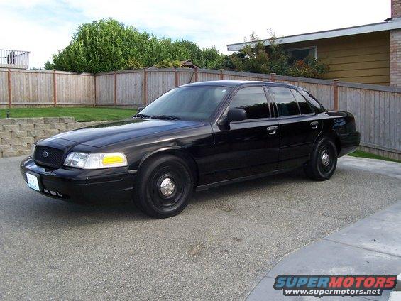 Black sedan parked in a driveway. Looks like a 2003 Ford Crown Victoria