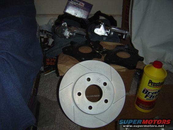 Slotted brake rotor, brake calipers, mounting brackets, and a bottle of Prestone brake fluid