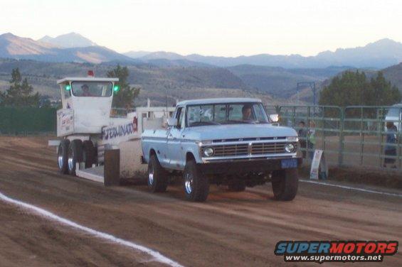 Light blue pickup truck with a trailer in tow on a dirt track