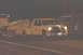 1994 Ford F-150 - A white GMC pickup truck with a tow bed is seen from the front-right angle at night, with another vehicle partially visible to the left.