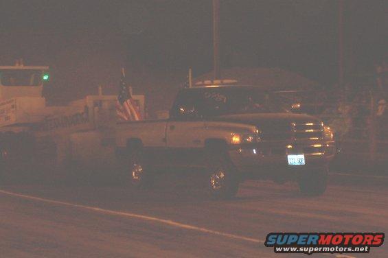 Pickup truck with American flag in bed, seen at night. License plate is visible