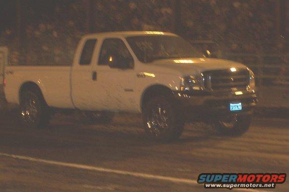 White pickup truck, 3/4 front view, with aftermarket wheels and a license plate reading 'DRYSMY'