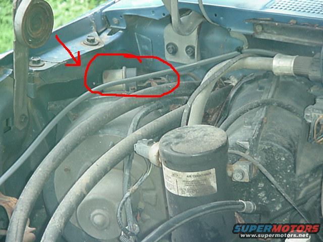 Engine bay with red circle around a component, arrow pointing to bracket