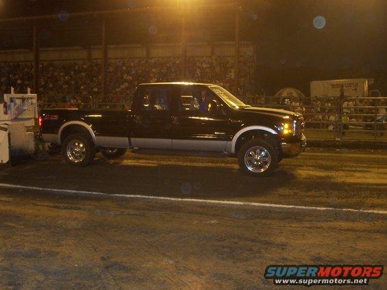 Black and silver Ford F-250 Super Duty truck with chrome wheels, seen from the side at night