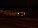 1994 Ford F-150 - A white pickup truck with decals tows a trailer in the dark, with headlights illuminated.