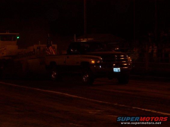 Dodge Ram pickup truck with an American flag on the bed, pulling a trailer at night