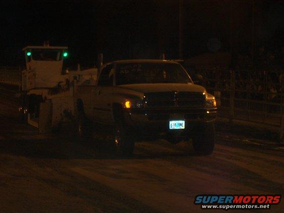 Dodge Ram pickup truck with a white tow vehicle behind it at night. License plate reads 61815NE