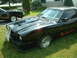 1978 Ford Mustang II - A black 1978 Ford Mustang II coupe is parked on a lawn, with a 'For Sale' sign in front and another black car visible behind it.