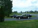 1978 Ford Mustang II - Two black 1978 Ford Mustang II cars are parked side-by-side on a grassy area next to a road.