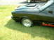 1978 Ford Mustang II - A black 1978 Ford Mustang II Cobra II is parked on grass, showing its hood scoop and side racing stripes.