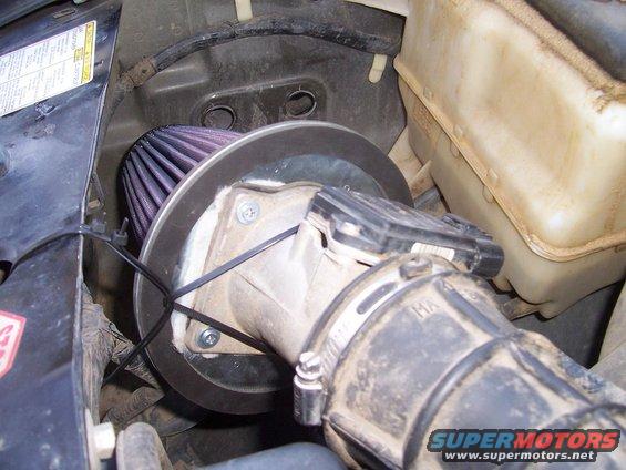 Engine bay part with purple air filter and metal adapter plate, zip-tied to black plastic housing