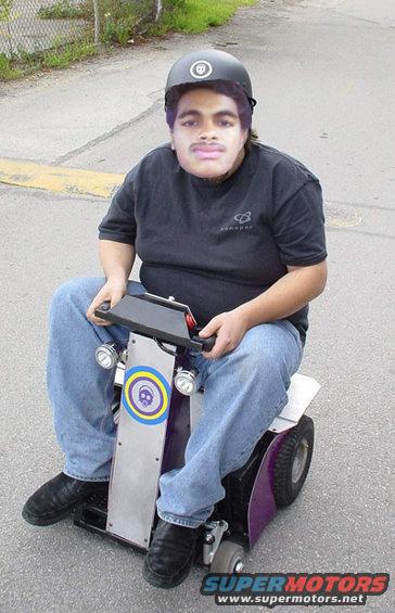 Person wearing a helmet and jeans on a purple and silver mobility scooter with lights
