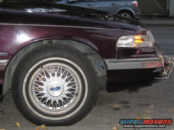 Damaged 1992 Ford Crown Victoria front fender and bumper. Ford wheel visible