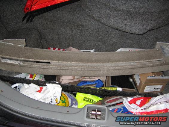 Car trunk interior with a reflective triangle, shopping bags, and a box