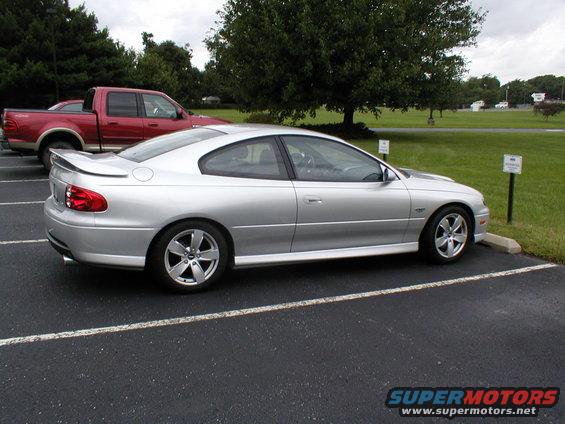 Silver coupe parked in a lot, side view