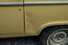 1972 Ford Bronco - The side panel of a yellow 1972 Ford Bronco shows a significant dent and rust spots, particularly around the wheel well.