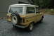 1972 Ford Bronco - A yellow 1972 Ford Bronco is parked on a gravel driveway, showing its rear and side profile.