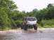 2000 Ford Excursion - Rear view of a lifted 2000 Ford Excursion with oversized tires navigating through a wet, muddy area.