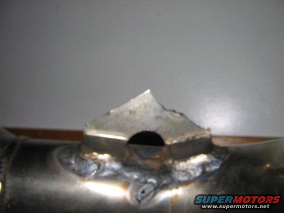 Welded metal part with a triangular tab and a circular hole