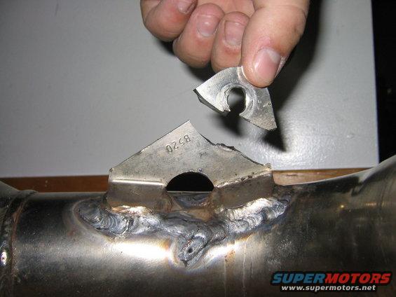 Broken metal mount on exhaust pipe, with part held in hand. Stamped 'B520'