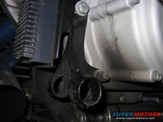 Close-up of a black metal bracket attached to a silver engine casing